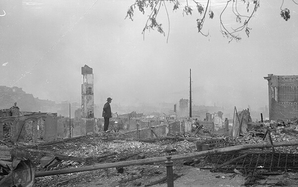 Photograph of a man in San Francisco as Chinatown is nothing but a flat pile of rubble - not a building in sight.